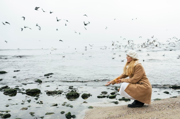 Free photo side view of woman outdoors at the beach in winter