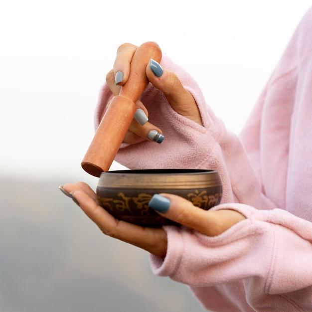 Free photo side view of woman outdoors holding singing bowl