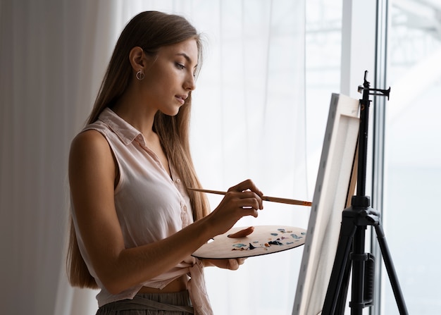 Free photo side view woman painting at home