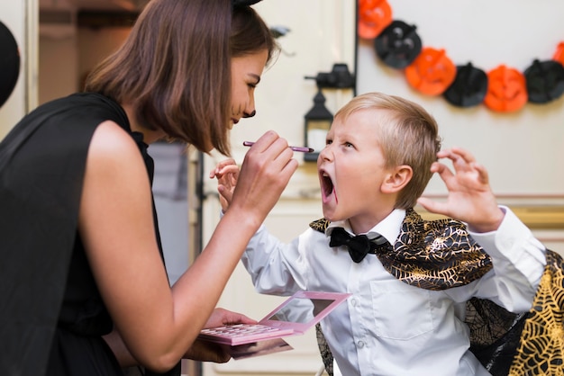 Side view woman painting kid's face