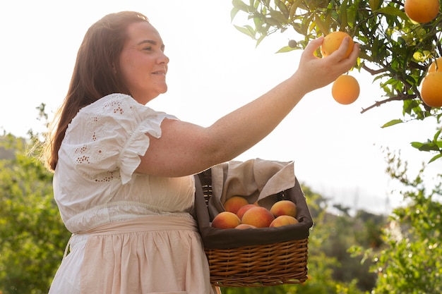 Free photo side view woman picking fruits