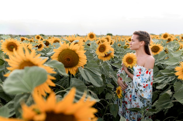 Side view woman posing in sunflower field