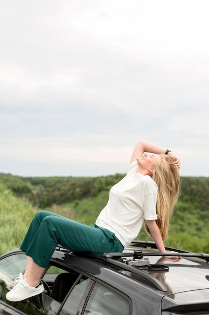 Side view of woman posing on top of car