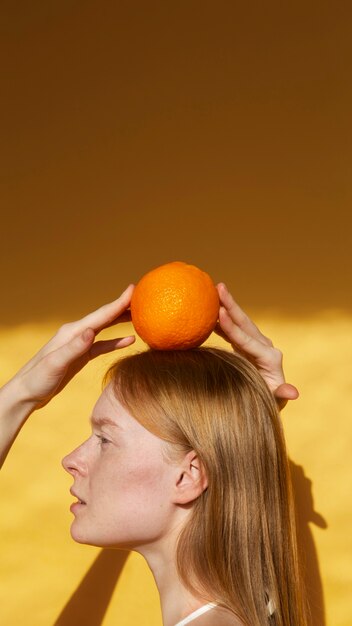 Side view woman posing with orange