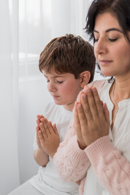 Side view of woman praying with her child