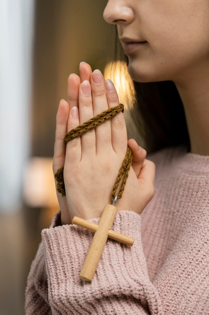 Side view of woman praying with wooden cross