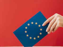 Free photo side view woman putting an european voting card in a box