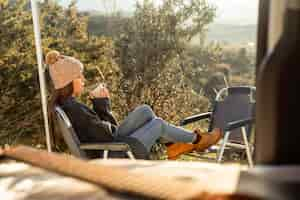 Free photo side view of woman relaxing next to car while on a road trip