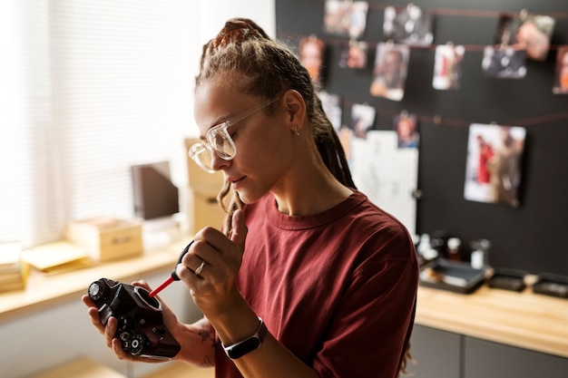 Free photo side view woman repairing photo camera