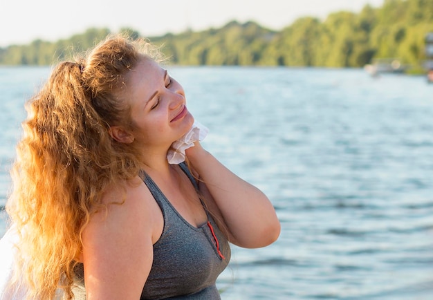 Side view of woman resting after working out by the lake with copy space