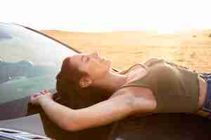 Free photo side view of woman resting on the car while outdoors