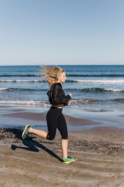 Side view of woman running at the beach