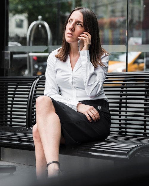 Side view woman sitting on a bench with phone