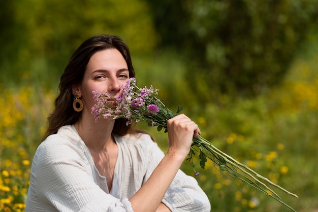 Free Photo side view woman smelling flowers