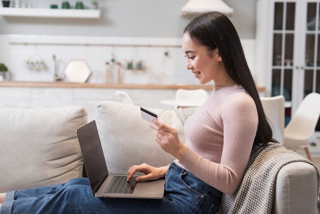 Free photo side view of woman on sofa shopping online