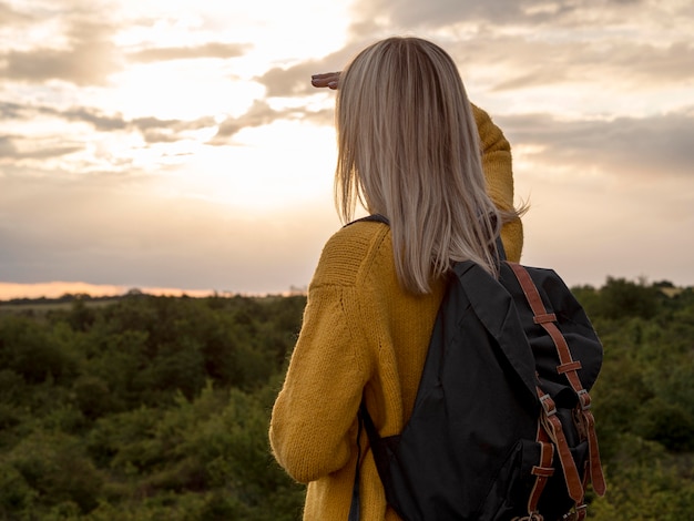 Free photo side view woman at sunset on mountain