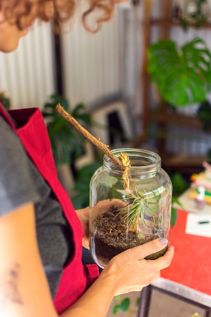 Free photo side view woman taking care of plant in jar