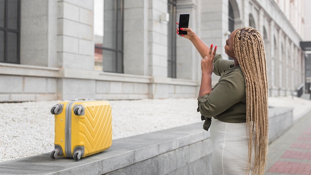 Free photo side view woman taking a selfie while traveling with copy space