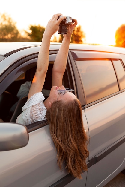 Free Photo side view of woman taking a selfie with camera while in the car