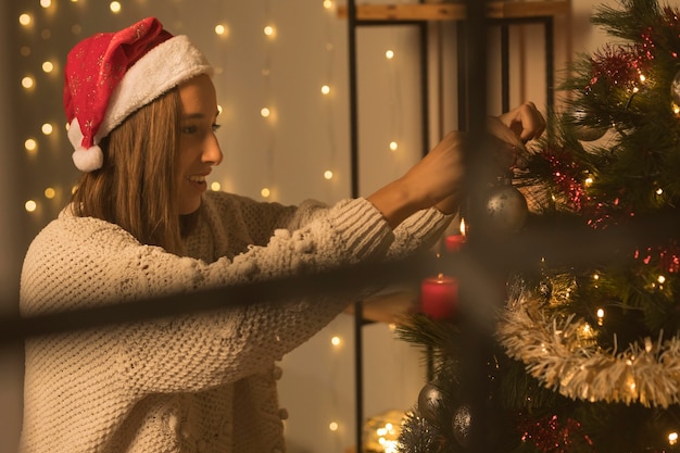 Free photo side view of woman through window decorating christmas tree