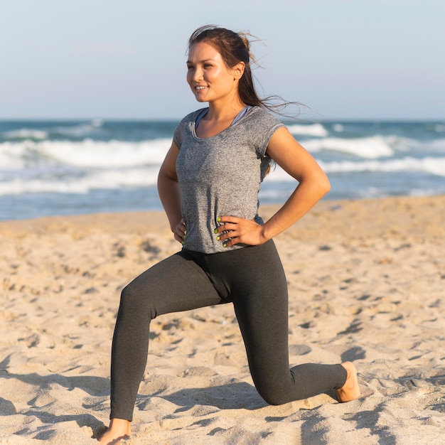 Free photo side view of woman training on the beach