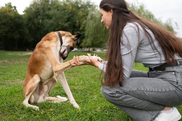 Free photo side view woman training dog outdoors