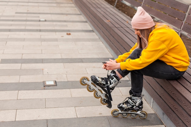 Side view of woman tying strings on roller blades