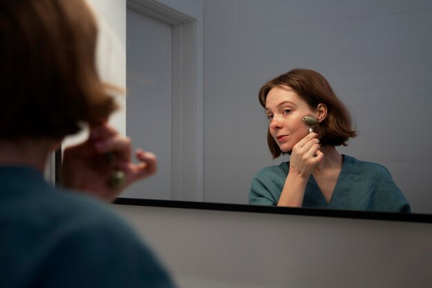 Side view woman using face roller for massage