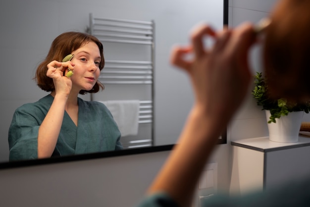 Side view woman using face roller for massage