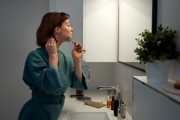 Side view woman using face roller for massage