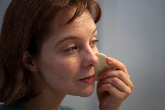 Side view woman using gua sha for massage