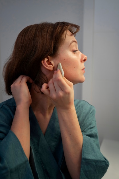 Side view woman using gua sha for massage