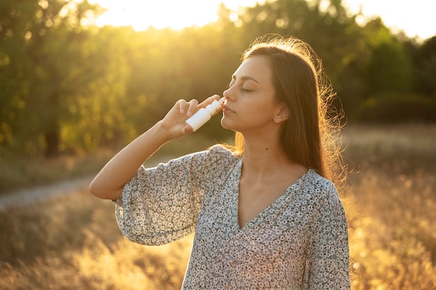 Free photo side view woman using nasal spray