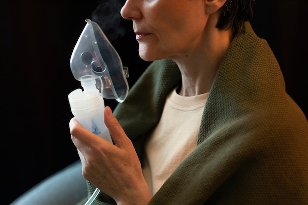 Free photo side view woman using nebulizer