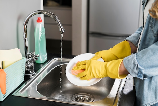 Side view of woman washing a plate in the sink