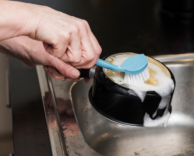 Free Photo side view of woman washing a pot