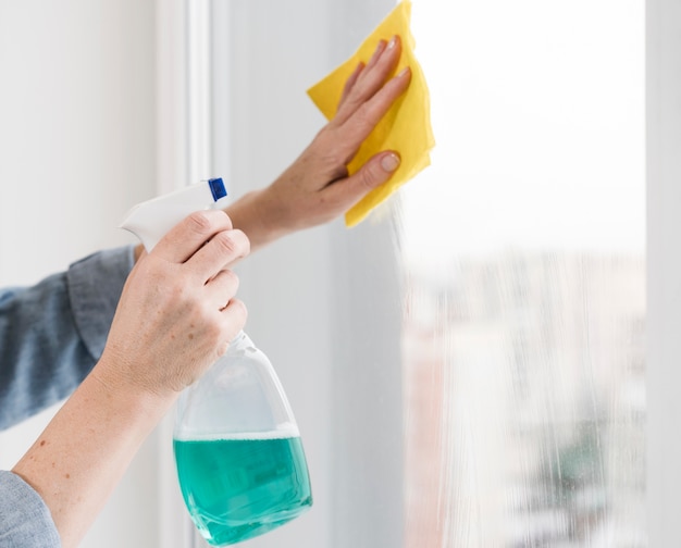 Free photo side view of woman washing window