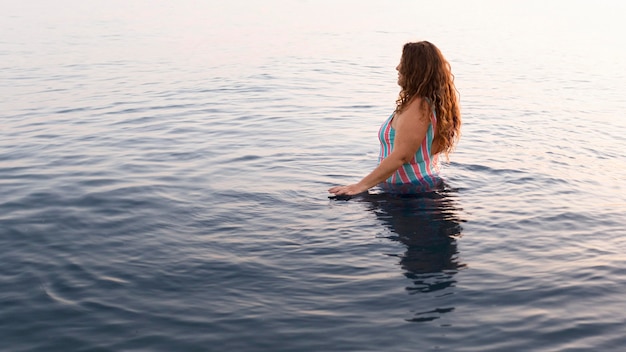 Free photo side view of woman in the water at the beach