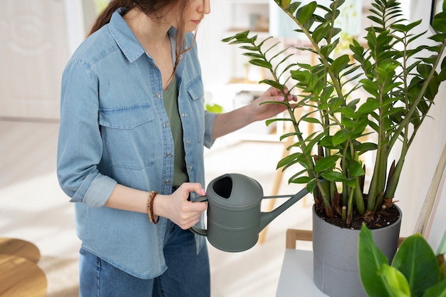 Free photo side view woman watering plant at home