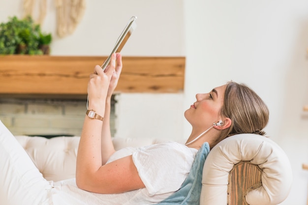 Side view of woman wearing headphone looking at digital tablet