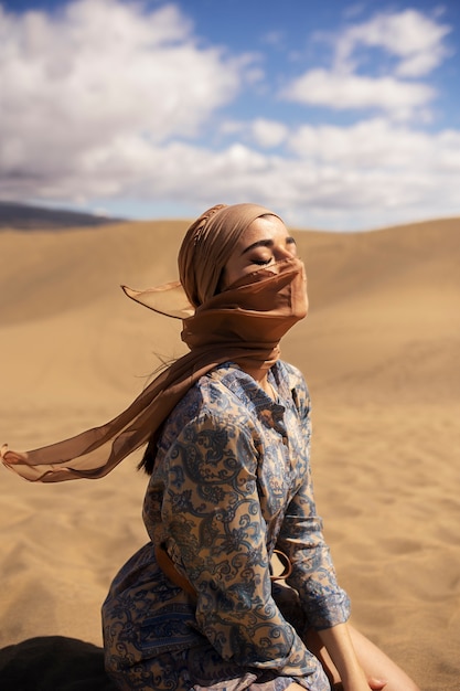 Free photo side view woman wearing scarf in desert