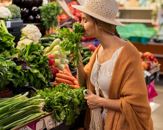 Side view woman wearing sun hat smelling leaves