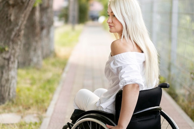 Free photo side view of woman in wheelchair outdoors with copy space