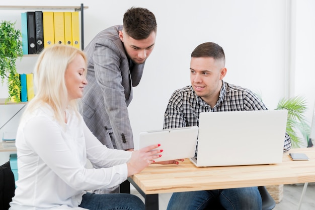 Side view of woman in wheelchair showing something to colleagues on tablet