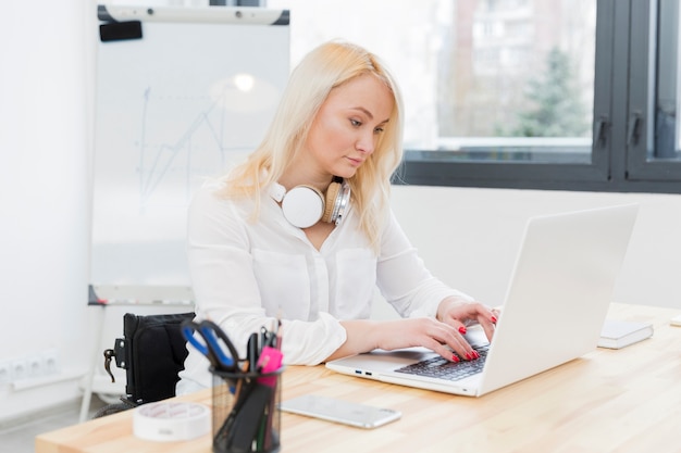 Side view of woman in wheelchair working on laptop