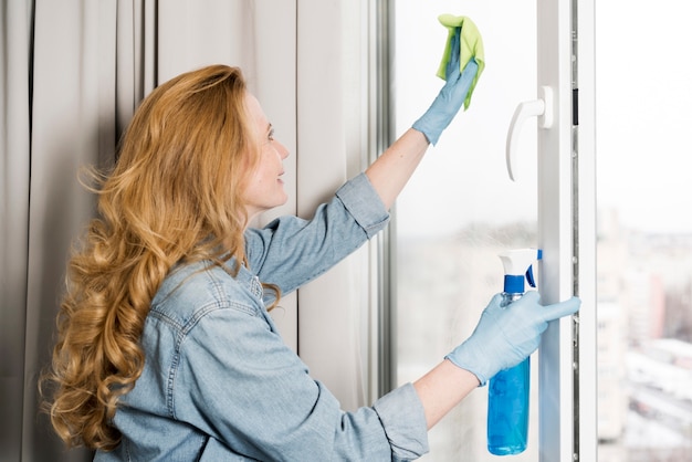 Free photo side view of woman wiping window