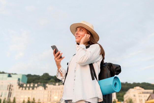 Side view of woman with backpack and smartphone traveling