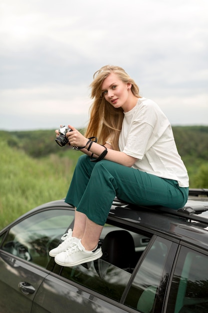 Side view of woman with camera on top of car