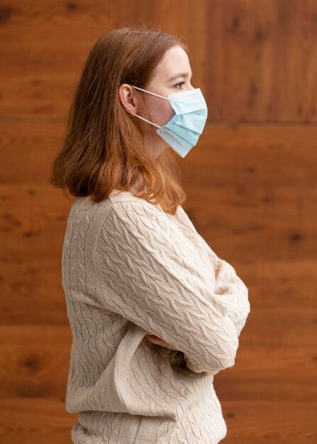 Side view of woman with crossed arms wearing a medical mask