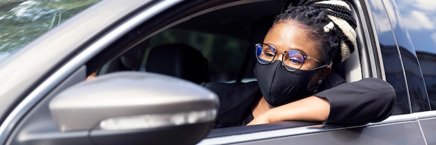 Side view of woman with face mask driving her car